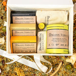 Organic Terra Co. Signature Gift Collection in an open gift box — three botanical soap bars, Botanical Butter, lip balm and soap saver pouch