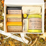Organic Terra Co. Signature Gift Collection in an open gift box — three botanical soap bars, Botanical Butter, lip balm and soap saver pouch