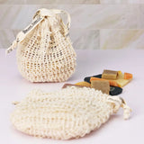 ORGANIC TERRA CO.® sisal drawstring soap pouch and oval sisal soap bag displayed with assorted handcrafted botanical soap bar samples on marble tile surface