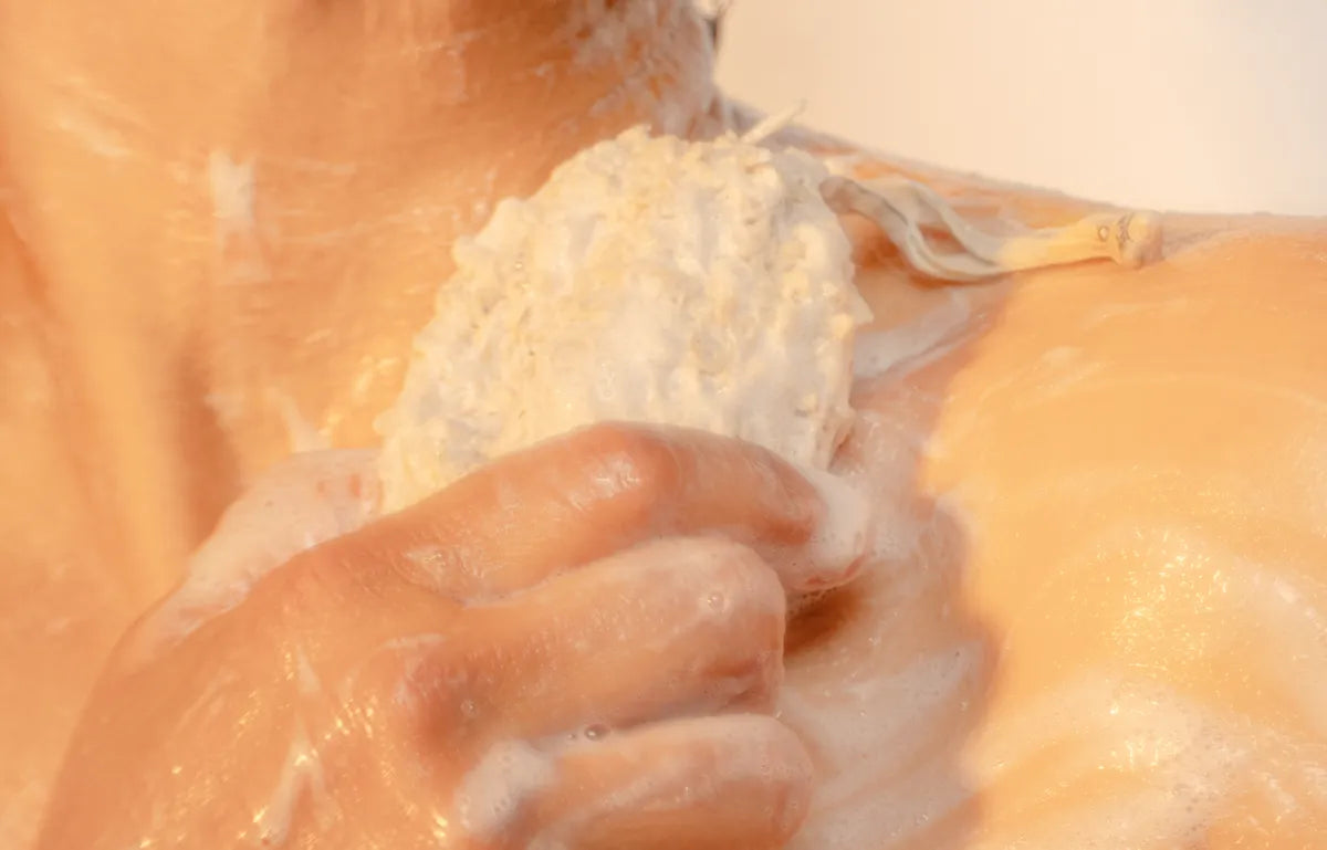 Hands using ORGANIC TERRA CO.®natural sisal soap exfoliating pouch to lather botanical soap bar on skin under shower water