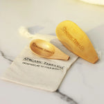 ORGANIC TERRA CO.® engraved wooden spoon and wooden spatula on branded cotton muslin pouch displaying From Nature To Your Body trademark on marble surface