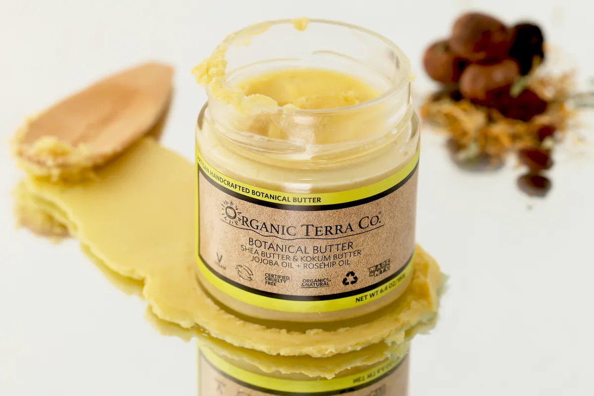 ORGANIC TERRA CO.® Butter with shea butter and kokum butter showing rich creamy texture with wooden spatula and rosehip berries on white background