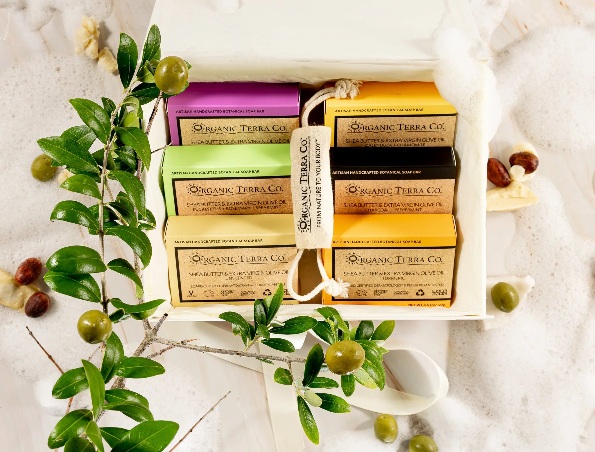 Organic Terra Co. Botanical Cleansing Collection gift box holding six soap bars, styled with fresh olive branches and a drawstring sachet.