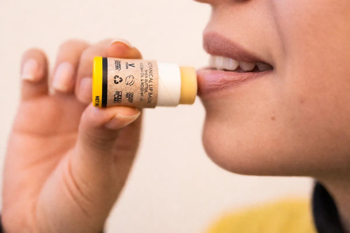 Woman applying ORGANIC TERRA CO.® Botanical Lip Balm with shea butter jojoba oil and rosehip oil in closeup lifestyle shot