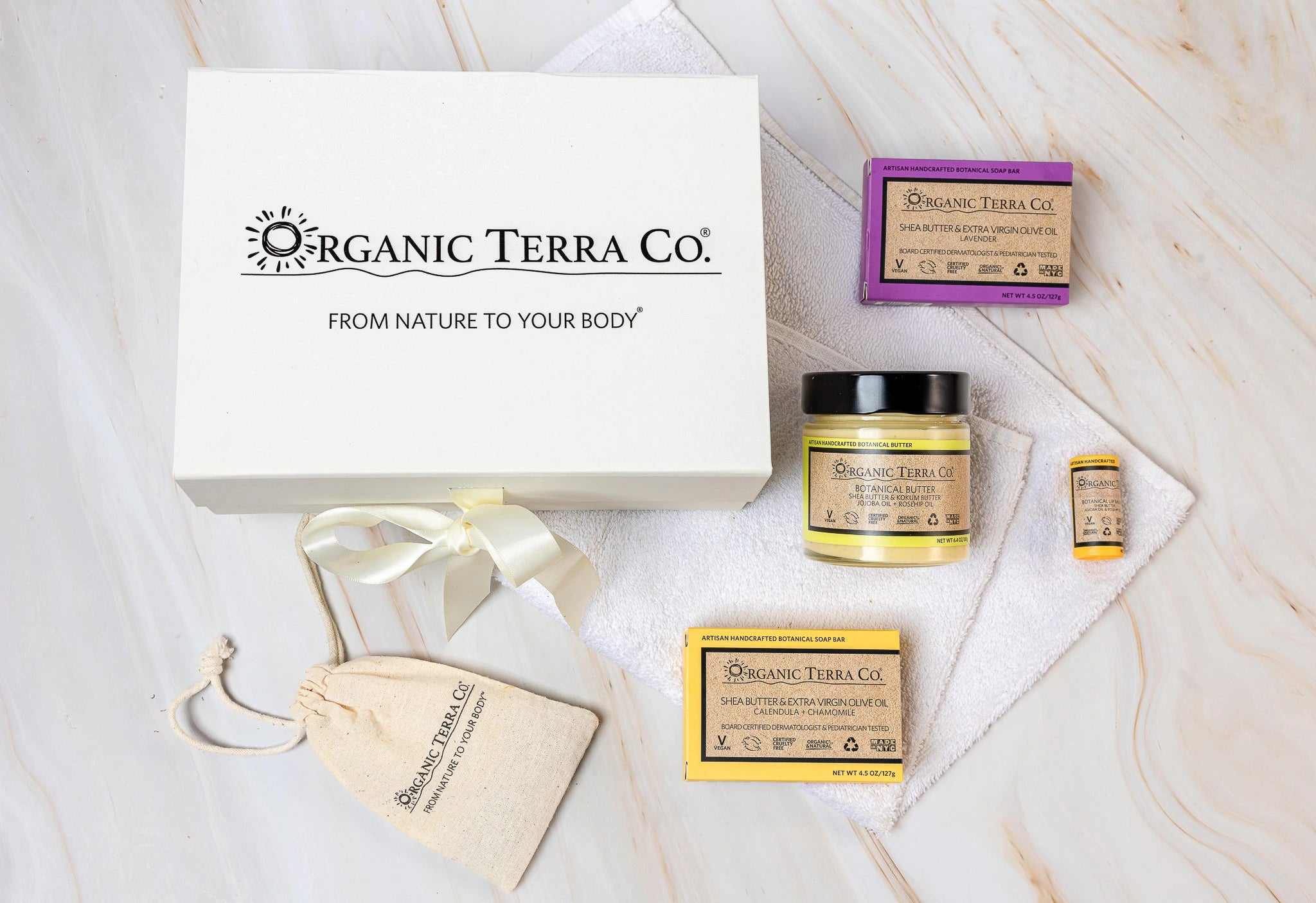 Organic Terra Co. Daily Collection — white gift box with ribbon, two botanical soap bars, 6.4 oz Botanical Butter, lip balm and dried-lavender sachet on a soft towel