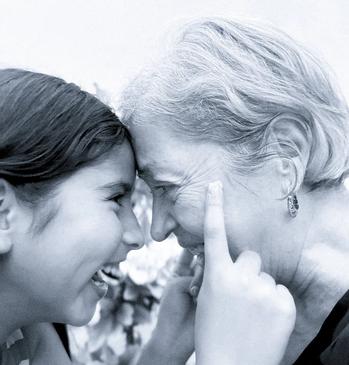 ORGANIC TERRA CO.® Black and white portrait of grandmother and granddaughter laughing together forehead to forehead representing the three generation family story behind Organic Terra Co. botanical skincare