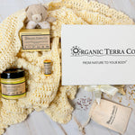 Organic Terra Co. Mama & Baby Collection — gift box with unscented botanical soap, Botanical Butter, lip balm and lavender pouch on a soft cream baby blanket with teddy bear