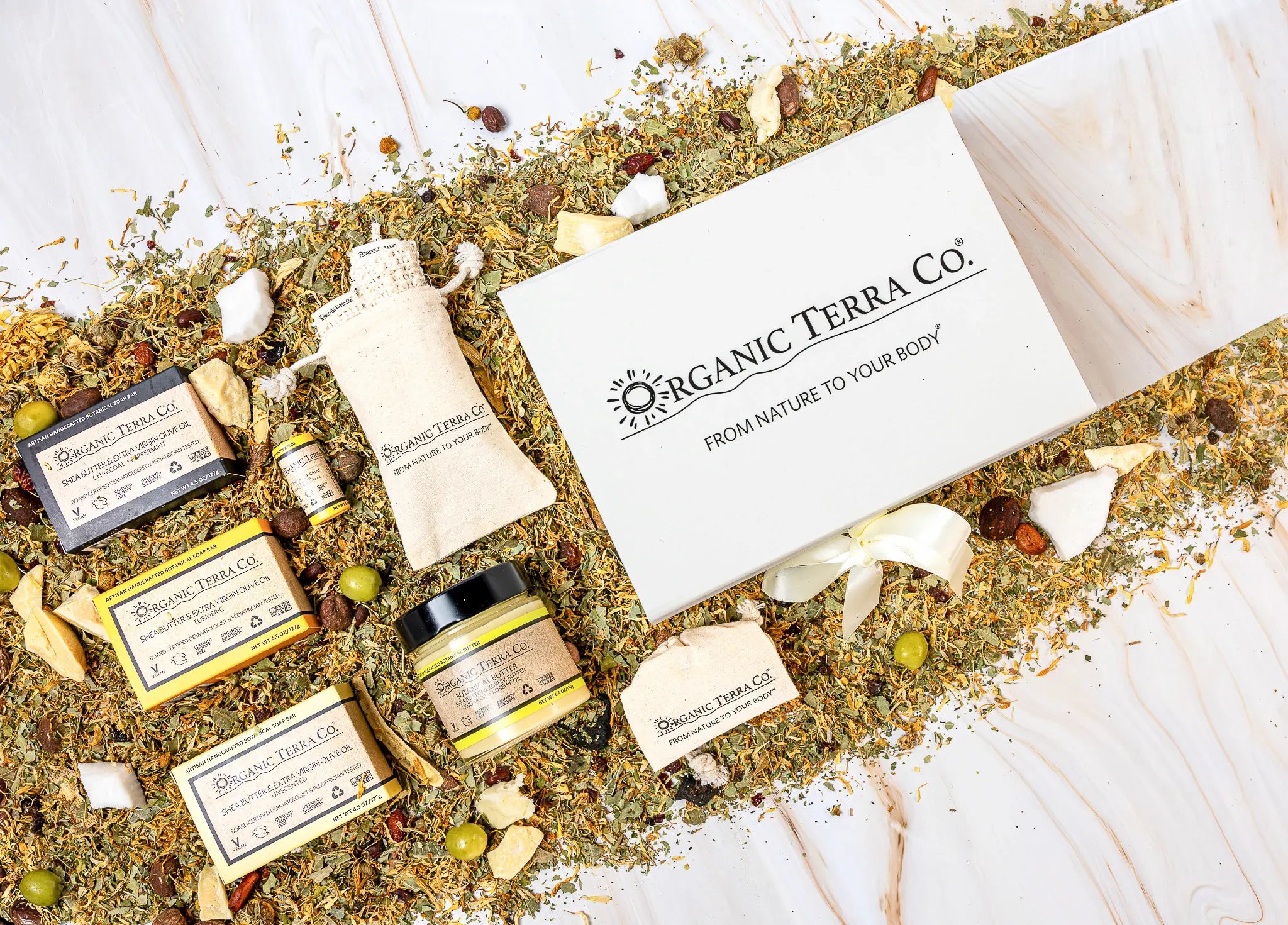 Organic Terra Co. Signature Gift Collection — white gift box with ribbon, three botanical soap bars, Botanical Butter, lip balm and sisal soap saver pouch