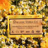 ORGANIC TERRA CO.® Butter Extra Virgin Olive Oil Calendula and Chamomile soap bar box surrounded by fresh chamomile buds and calendula flowers