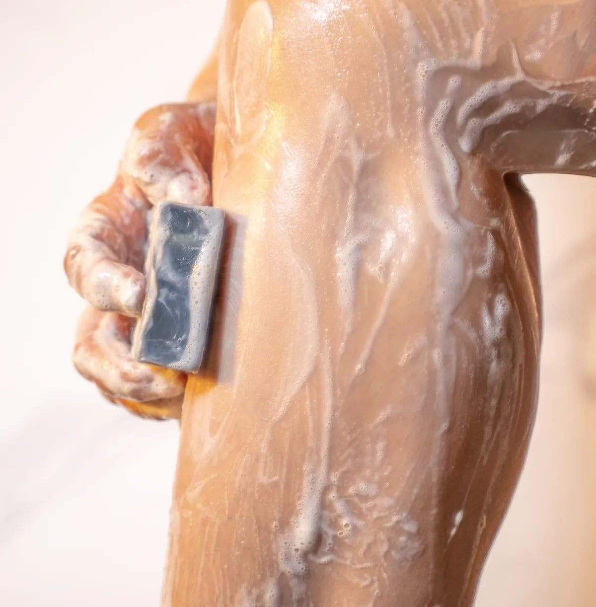 Hand lathering ORGANIC TERRA CO.® and Peppermint botanical soap bar on wet skin under shower water