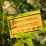 ORGANIC TERRA CO.® Butter Extra Virgin Olive Oil Eucalyptus Rosemary and Spearmint soap bar box resting on wet fresh eucalyptus rosemary and spearmint leaves
