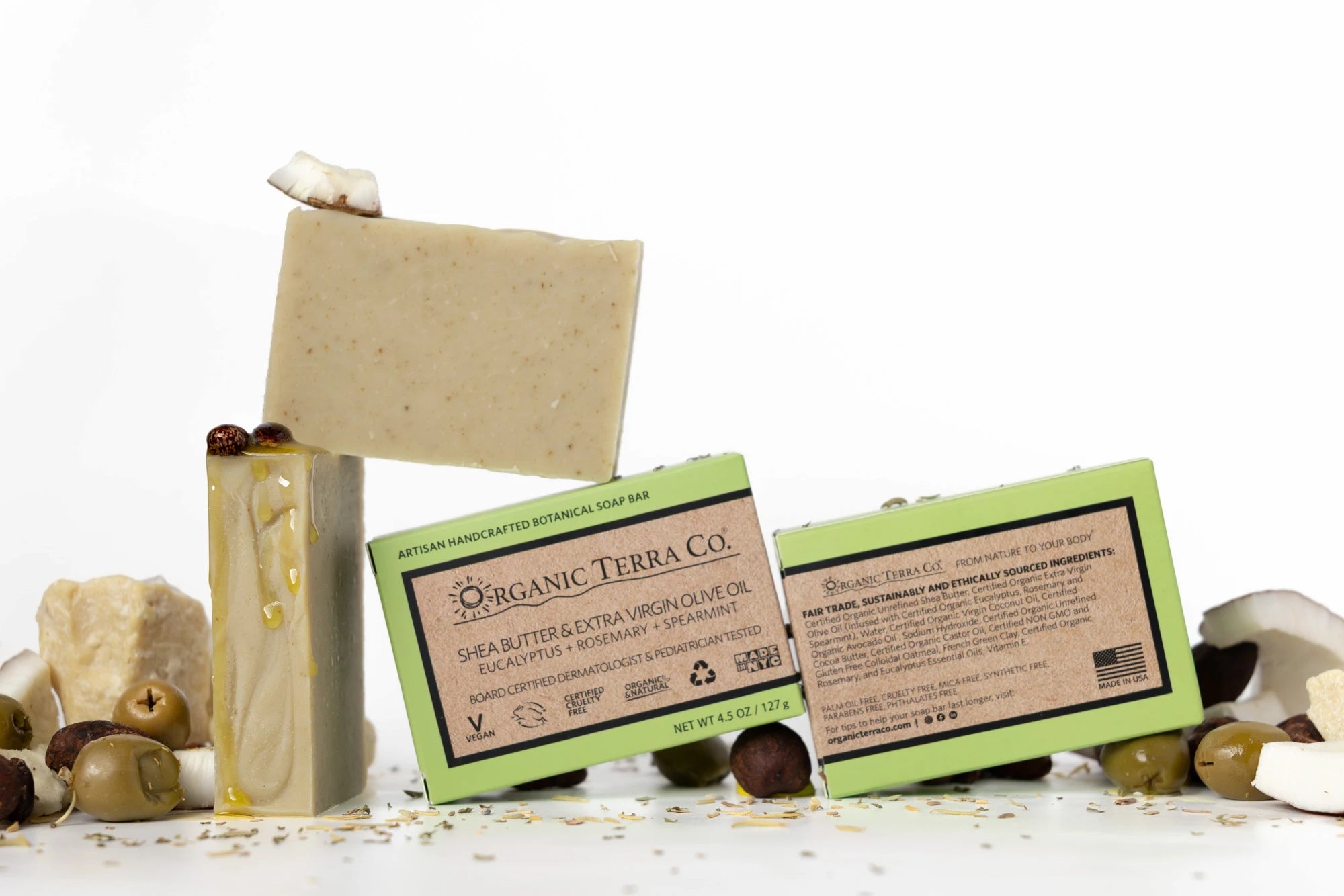 ORGANIC TERRA CO.®Shea Butter Extra
Virgin Olive Oil Eucalyptus Rosemary and
Spearmint soap bar front and back packaging with unwrapped bar and scattered shea nuts olives and cacao beans