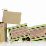 ORGANIC TERRA CO.®Shea Butter Extra
Virgin Olive Oil Eucalyptus Rosemary and
Spearmint soap bar front and back packaging with unwrapped bar and scattered shea nuts olives and cacao beans