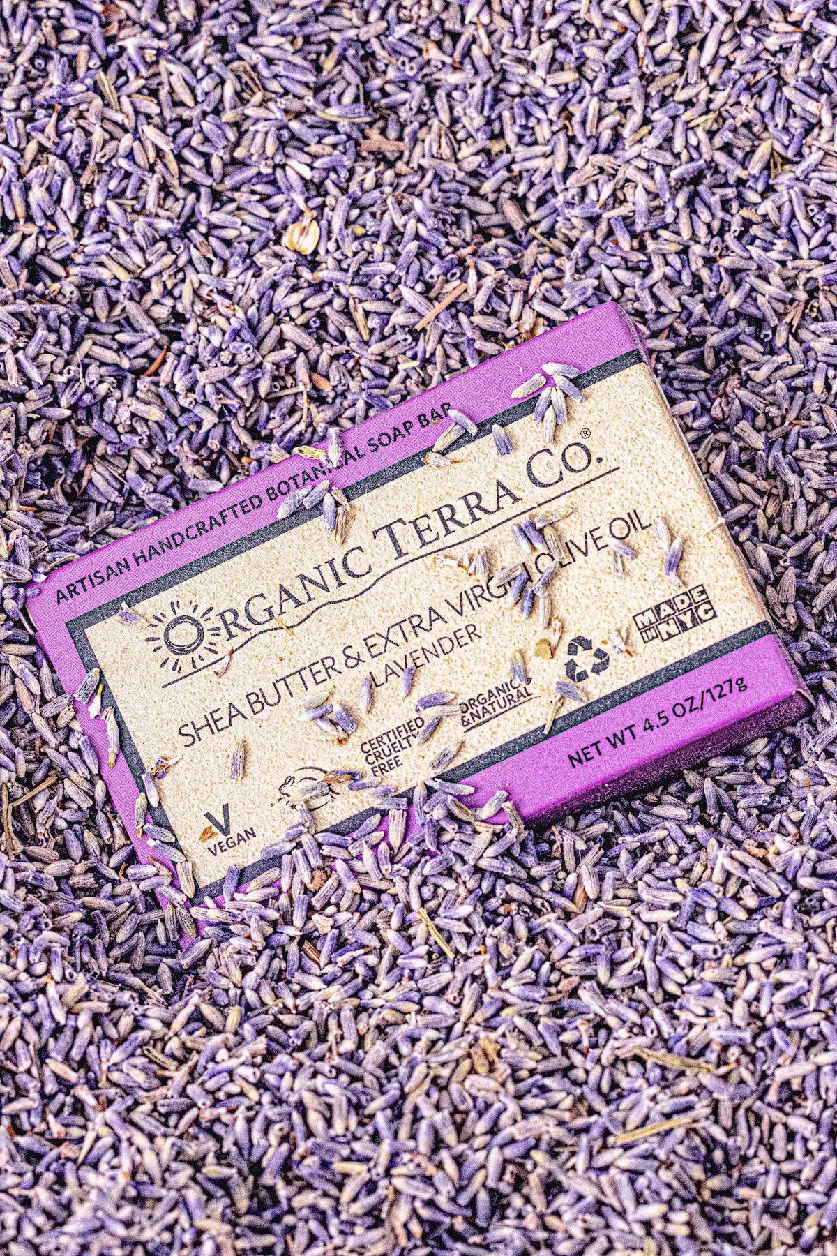 ORGANIC TERRA CO.®Shea Butter Extra Virgin Olive Oil Lavender soap bar box surrounded by and covered in dried lavender buds in overhead flatlay
