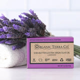 ORGANIC TERRA CO.®Shea Butter Extra Virgin Olive Oil Lavender soap bar box beside rolled white towel and large fresh lavender bouquet against white tile background
