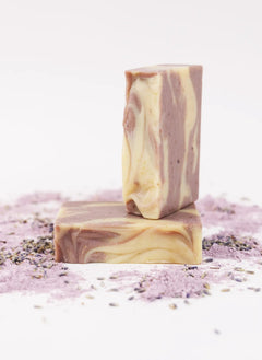 ORGANIC TERRA CO.®handcrafted Shea Butter Extra Virgin Olive Oil Lavender soap bars stacked surrounded by lavender powder and dried lavender buds on white background