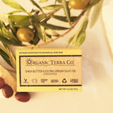 ORGANIC TERRA CO.®Shea Butter and Extra Virgin Olive Oil unscented soap bar box flatlay with fresh olive branch green olives shea nuts and raw shea butter on cream background