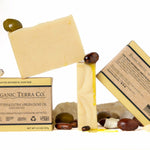ORGANIC TERRA CO,© Butter and Extra Virgin Olive Oil unscented soap bar showing front and back packaging with fair trade ingredients alongside unwrapped bar and shea nuts