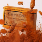 ORGANIC TERRA CO.®Shea Butter Extra Virgin Olive Oil Turmeric soap bar box emerging dramatically from turmeric powder cloud with fresh turmeric root pieces