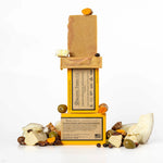 ORGANIC TERRA CO.® Extra Virgin Olive Oil Turmeric soap bar front and back packaging stacked with unwrapped bars and scattered turmeric root olives shea nuts and coconut